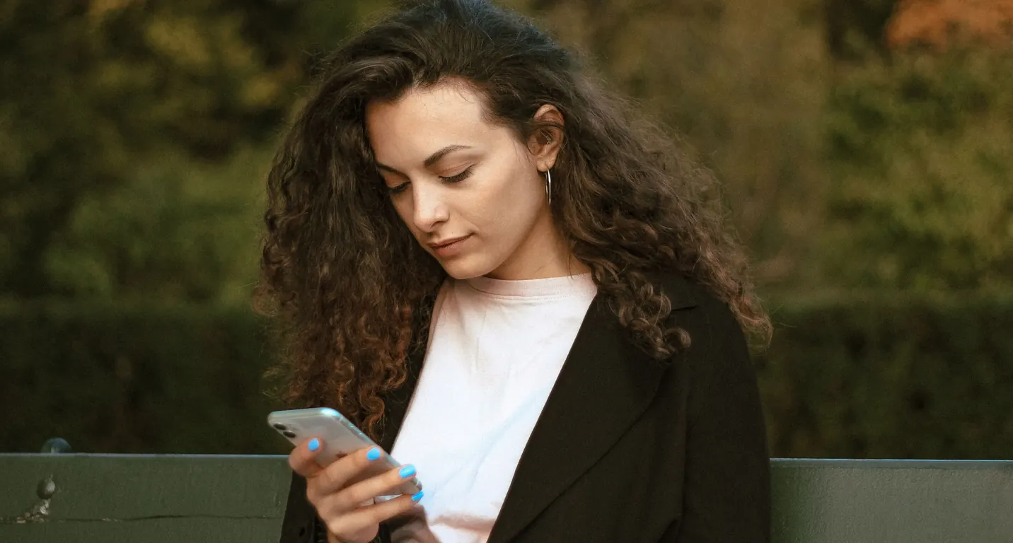A woman on a park bench looking at her phone.